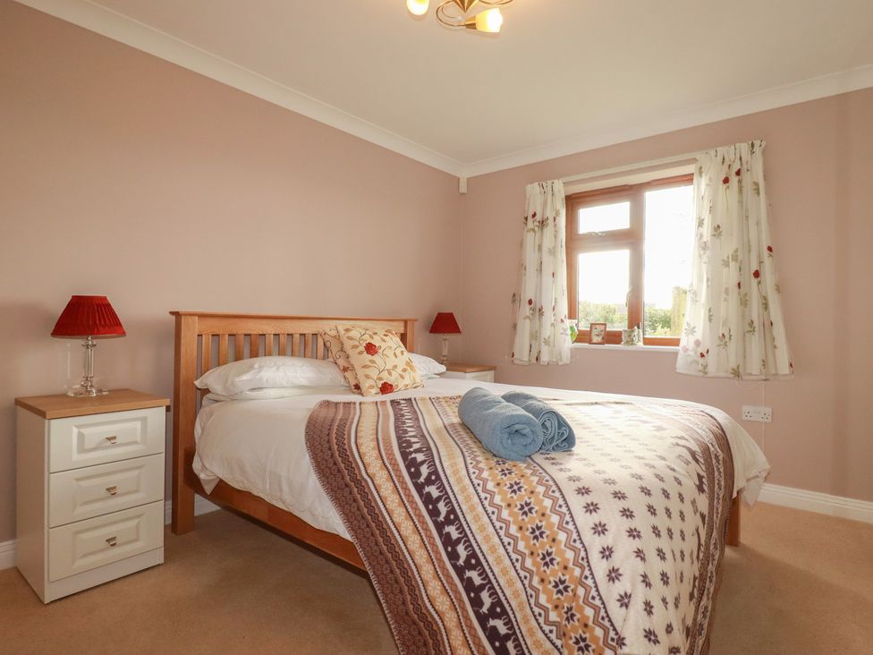 A bedroom with a bed and bedside table at Honeysuckle Rise in Looe