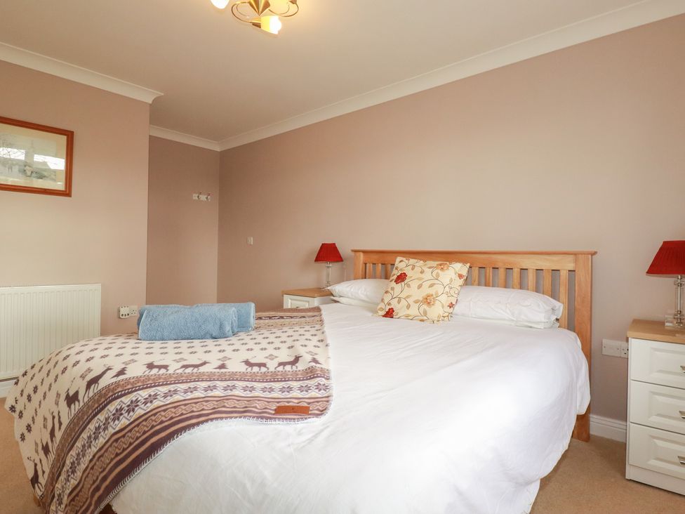 A bedroom with a bed and bedside tables at Honeysuckle Rise in Looe