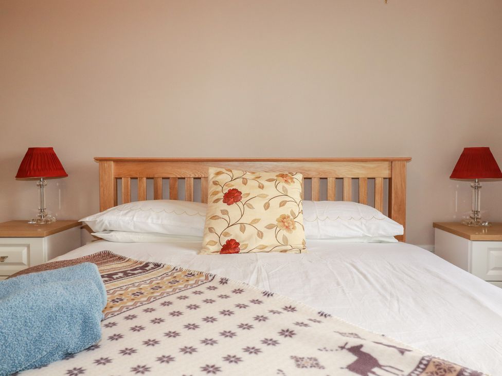 A bedroom with a bed and bedside lamps at Honeysuckle Rise in Looe