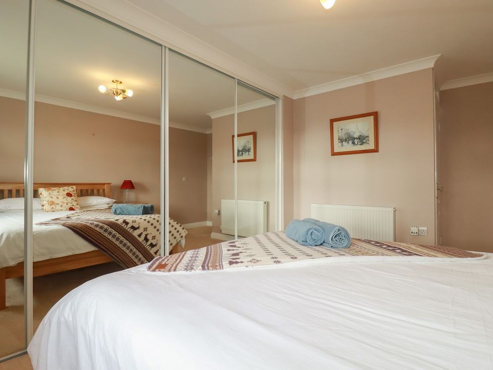 A bedroom with a bed, blanket, and towels at Honeysuckle Rise in Looe