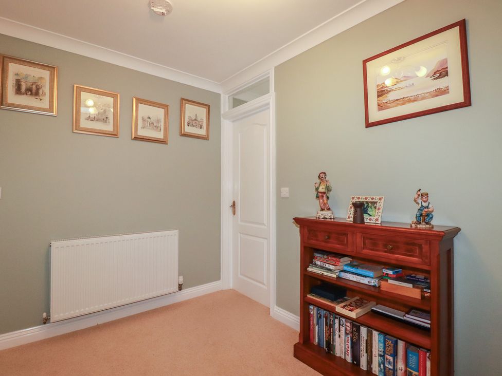 A hallway with pictures on the wall and a bookshelf at Honeysuckle Rise Looe