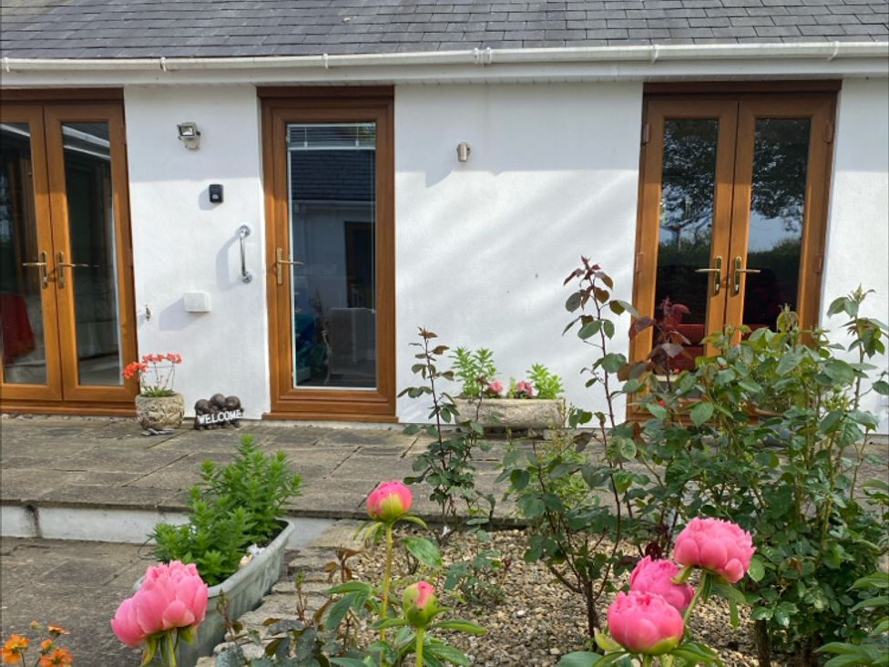 An outdoor area with doors and flowers at Honeysuckle Rise in Lanreath
