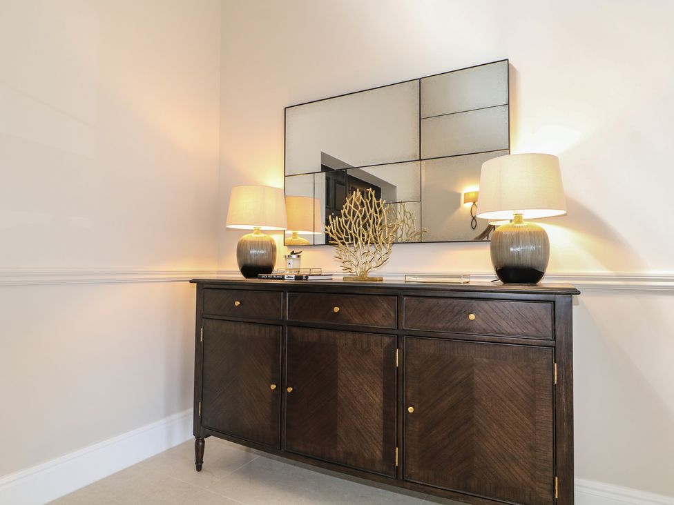 An entryway with a cabinet, lamps, and a mirror at Sea Estate House in Littlehampton
