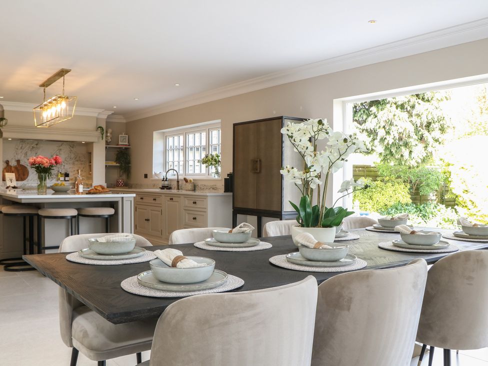 A kitchen with a dining area featuring a large table with plates and flowers at Sea Estate House in Littlehampton