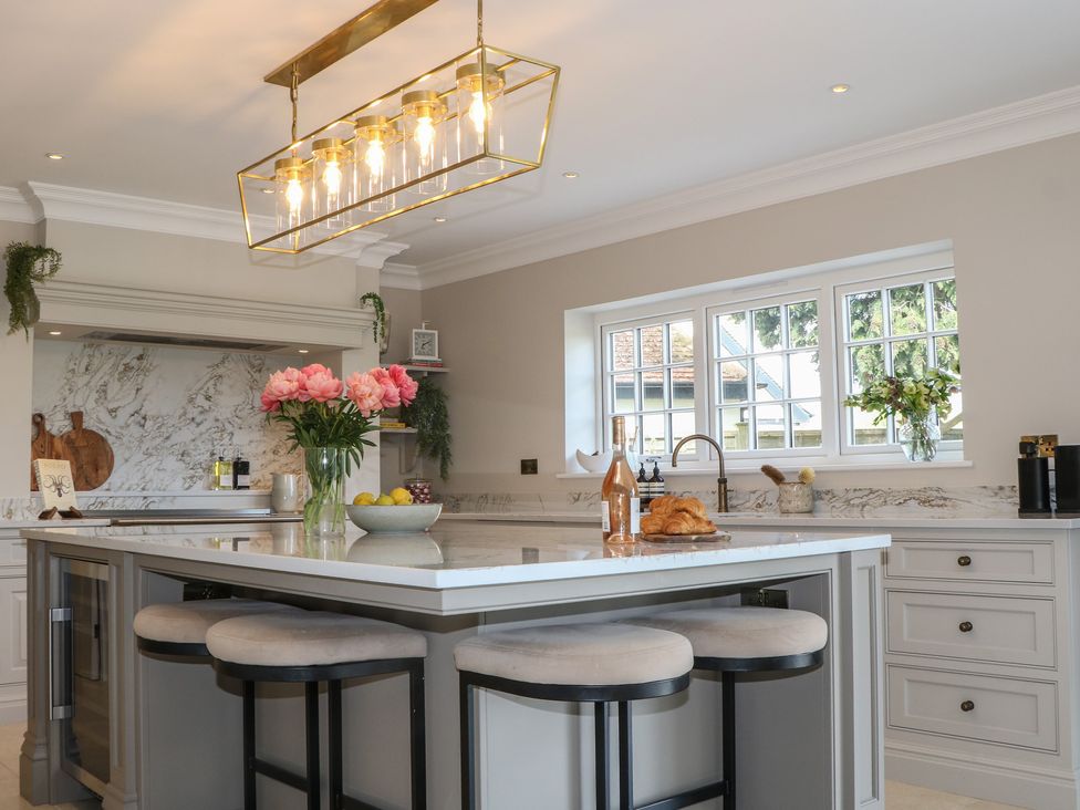 A kitchen with an island and bar stools at Sea Estate House in Littlehampton