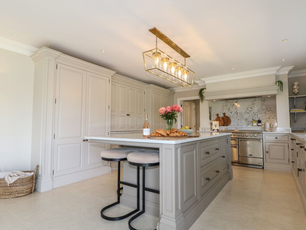 A kitchen with an island counter and bar stools at Sea Estate House in Littlehampton