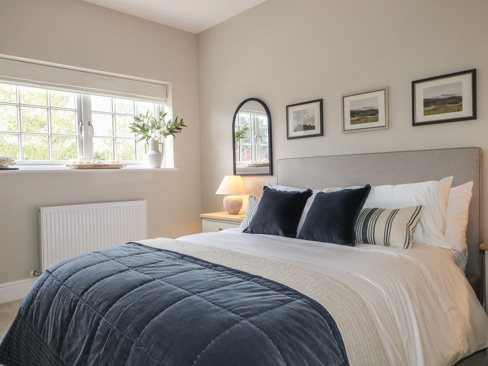 A bedroom with a bed, window, and mirror at Sea Estate House in Littlehampton