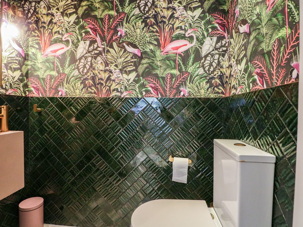 A bathroom with green wall tiles and a toilet at Sea Estate House in Littlehampton
