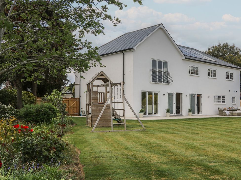 A house with a swingset and lawn at Sea Estate House in Littlehampton