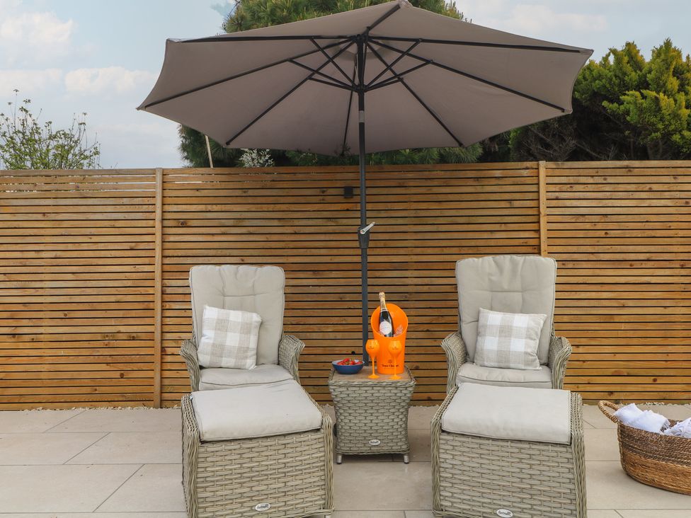 A seating area with deck chairs and a sunshade at Sea Estate House in Littlehampton