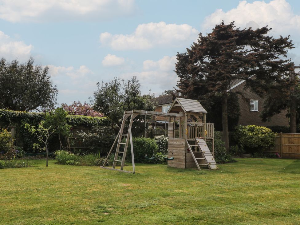 A garden with a swing set and playhouse at Sea Estate House in Littlehampton