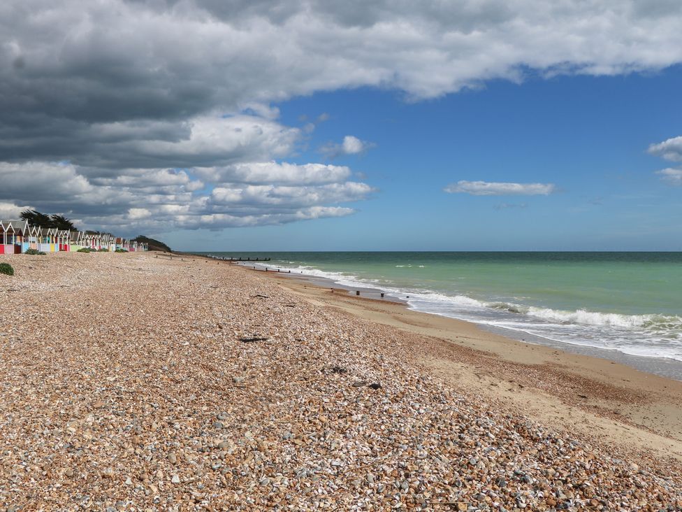 A beach with pebbles and colorful beach huts at Sea Estate House in Littlehampton