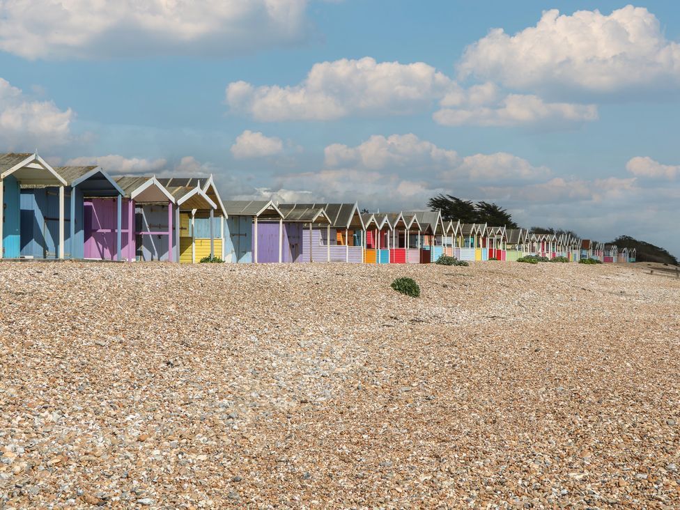 Beach huts lined up along the shore at Sea Estate House in Littlehampton