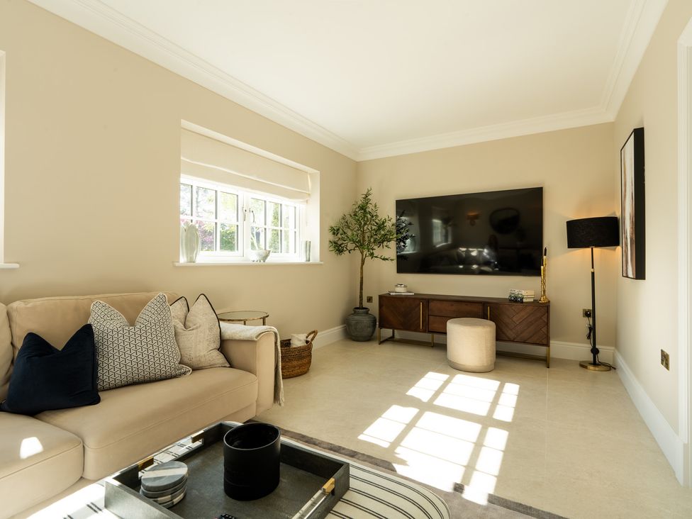 A living room with a sofa and television stand at Sea Estate House in Rustington