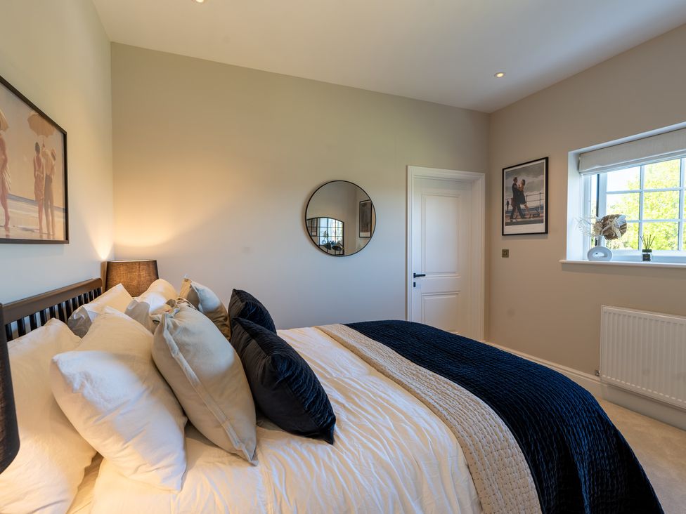 A bedroom with a bed, lamp, and mirror at Sea Estate House in Rustington