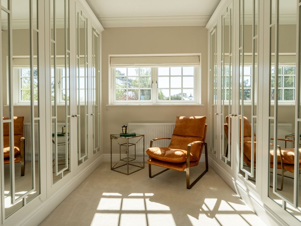 A dressing room with a chair and mirrors at Sea Estate House Rustington