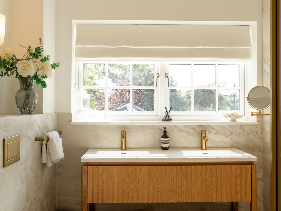A bathroom with a sink and flowers at Sea Estate House in Rustington