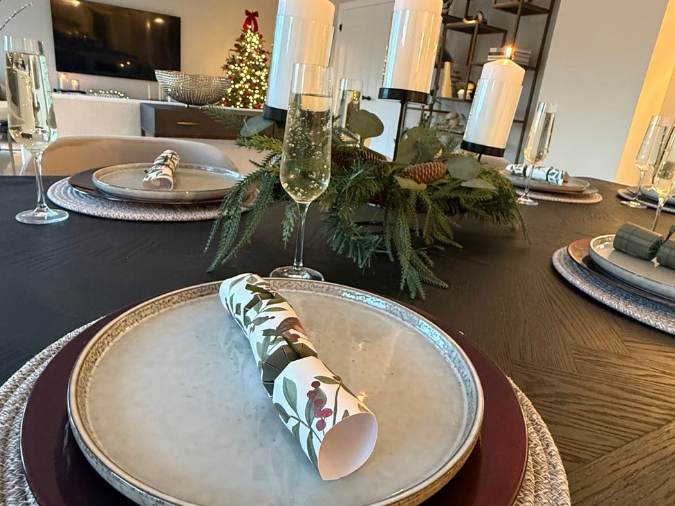 A dining table set with plates and glasses at Sea Estate House in Rustington