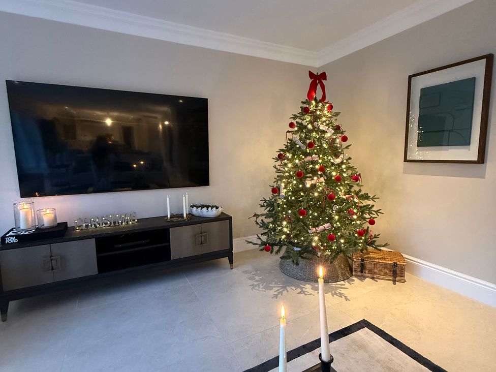A living room with a Christmas tree and television at Sea Estate House Rustington