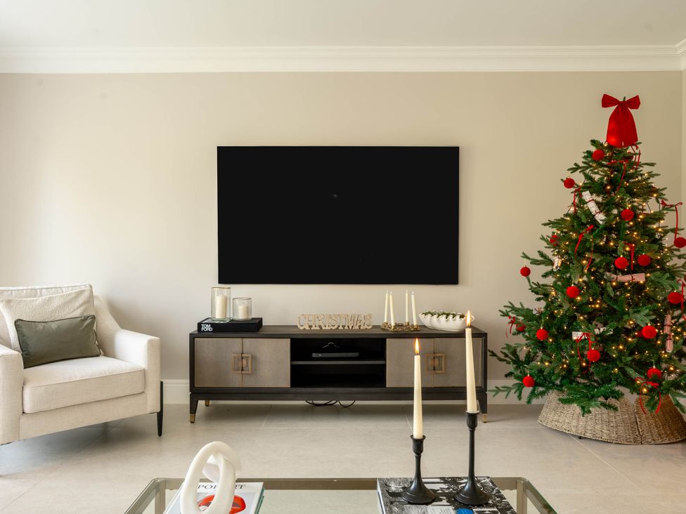 A living room with a sofa and a Christmas tree at Sea Estate House in Rustington