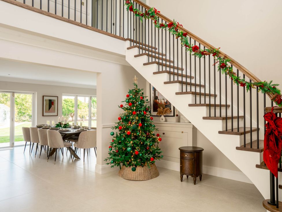 A dining room with a staircase and a Christmas tree at Sea Estate House in Rustington