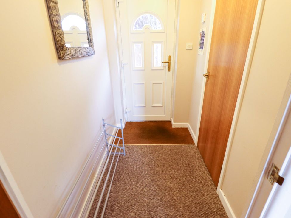 A hallway with a mirror and door at Grebe Cottage in Norwich