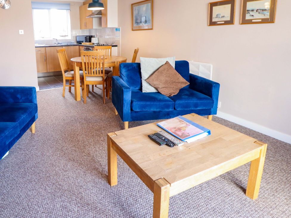 A living room with a blue sofa and wooden furniture at Grebe Cottage in Norwich