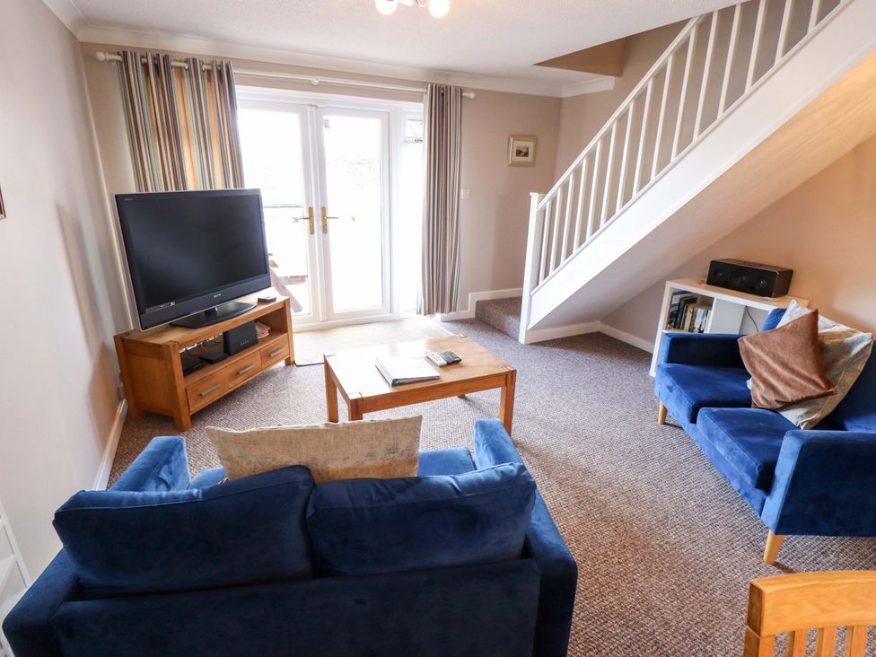 A living room with a television and seating area at Grebe Cottage in Norwich