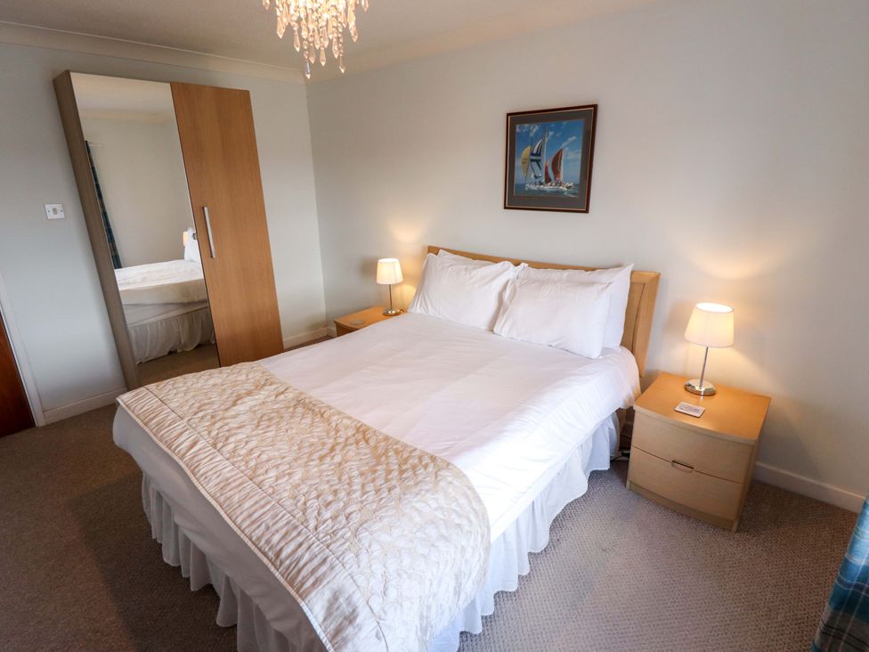 A bedroom with a bed and bedside table at Grebe Cottage in Norwich