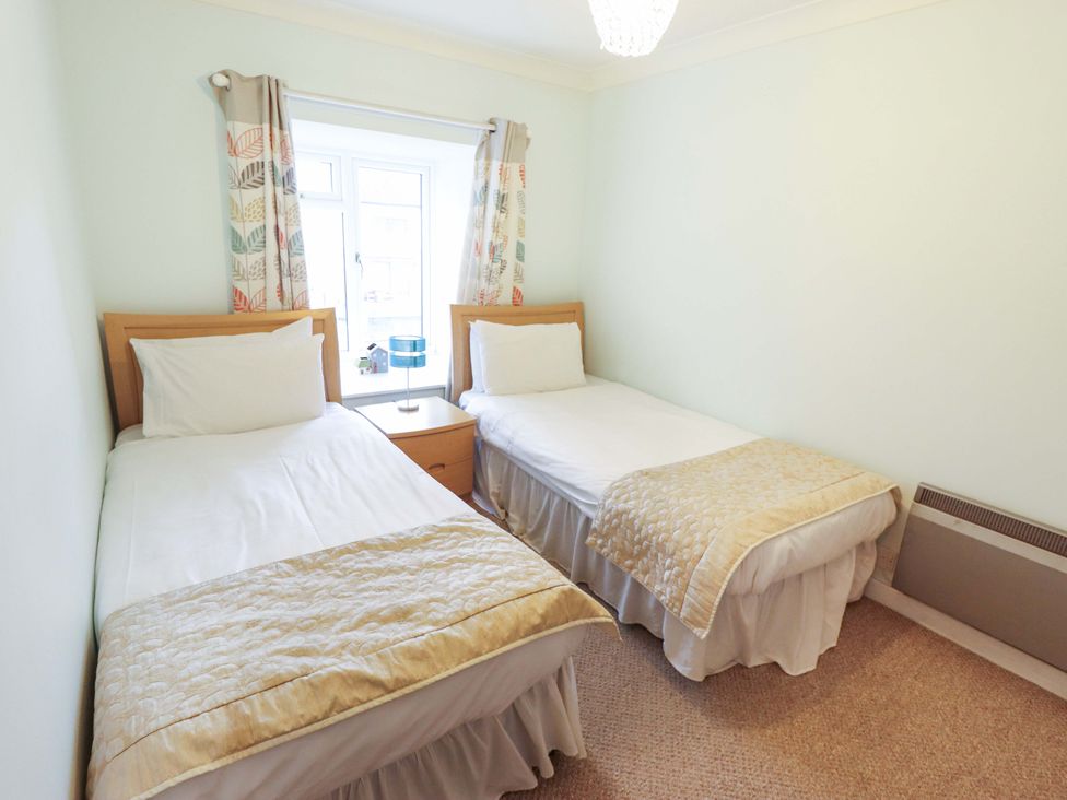 A bedroom with two single beds and a bedside table at Grebe Cottage in Norwich