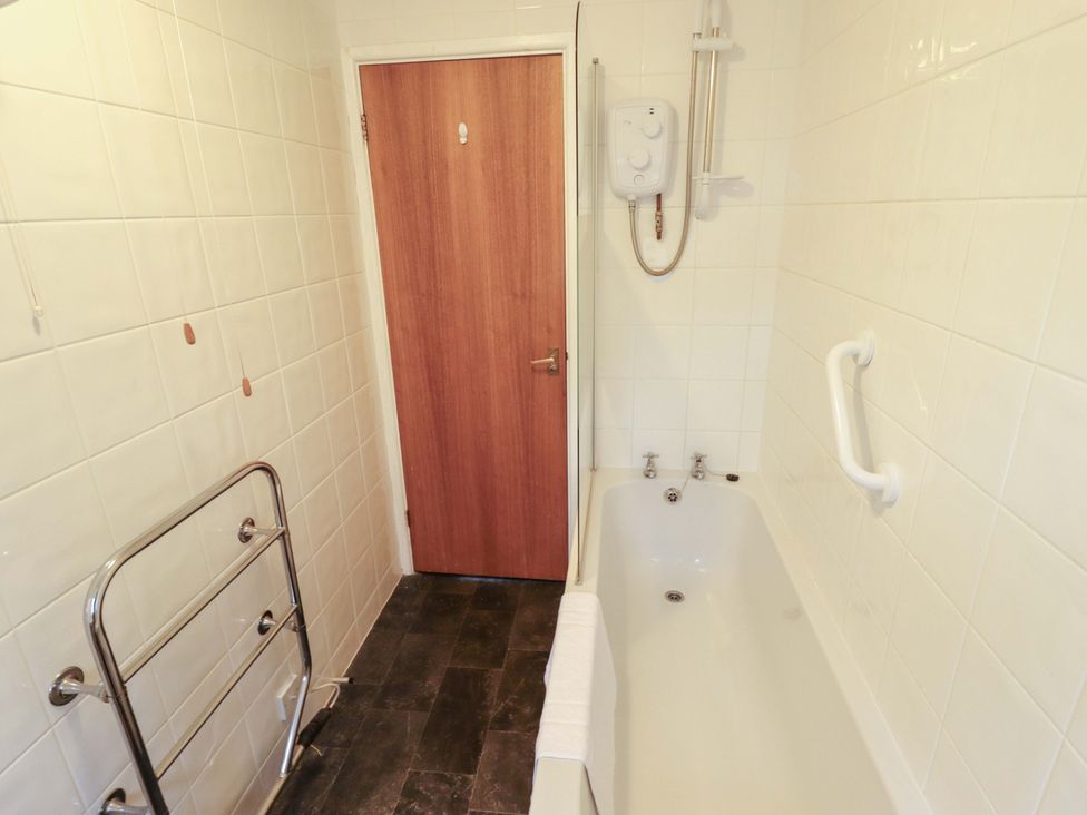 A bathroom with a bathtub and shower unit at Grebe Cottage in Norwich