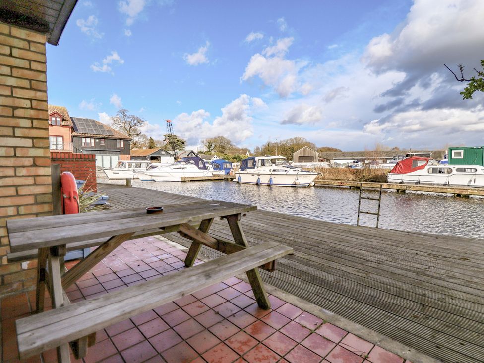 An outdoor seating area overlooking boats at Grebe Cottage in Norwich