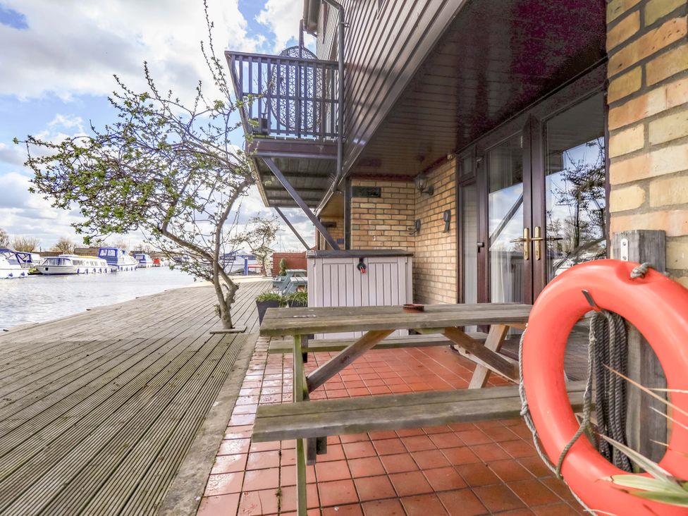 A patio area with a table and benches at Grebe Cottage in Norwich