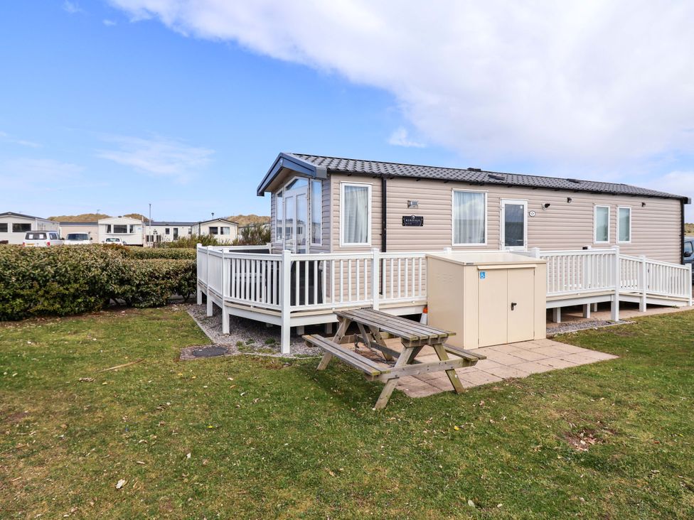 A caravan with decking and a picnic table at The Retreat in Prestatyn
