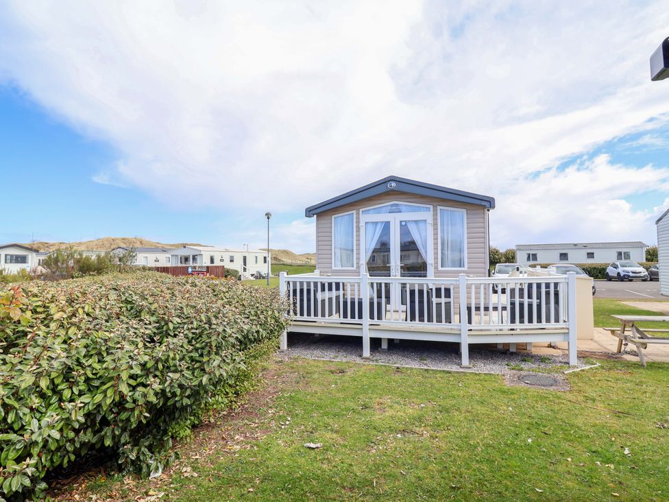 A caravan with a deck and lawn at The Retreat in Prestatyn