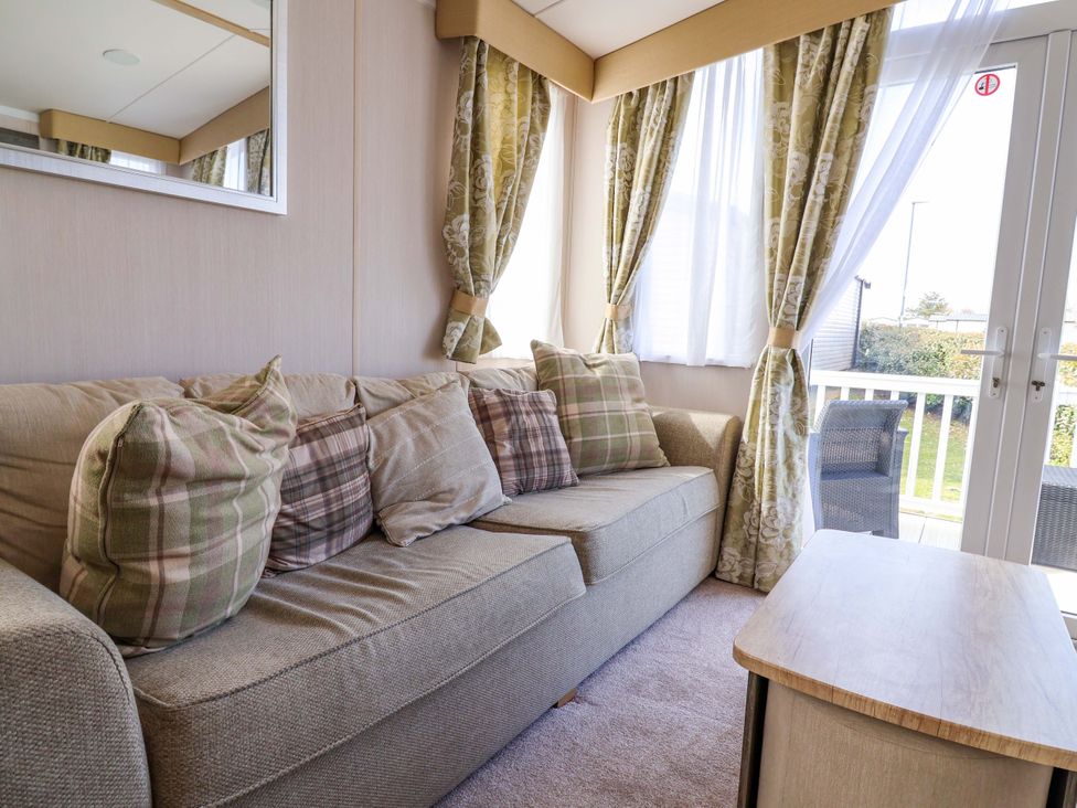 A living room with a sofa and cushions at The Retreat in Prestatyn