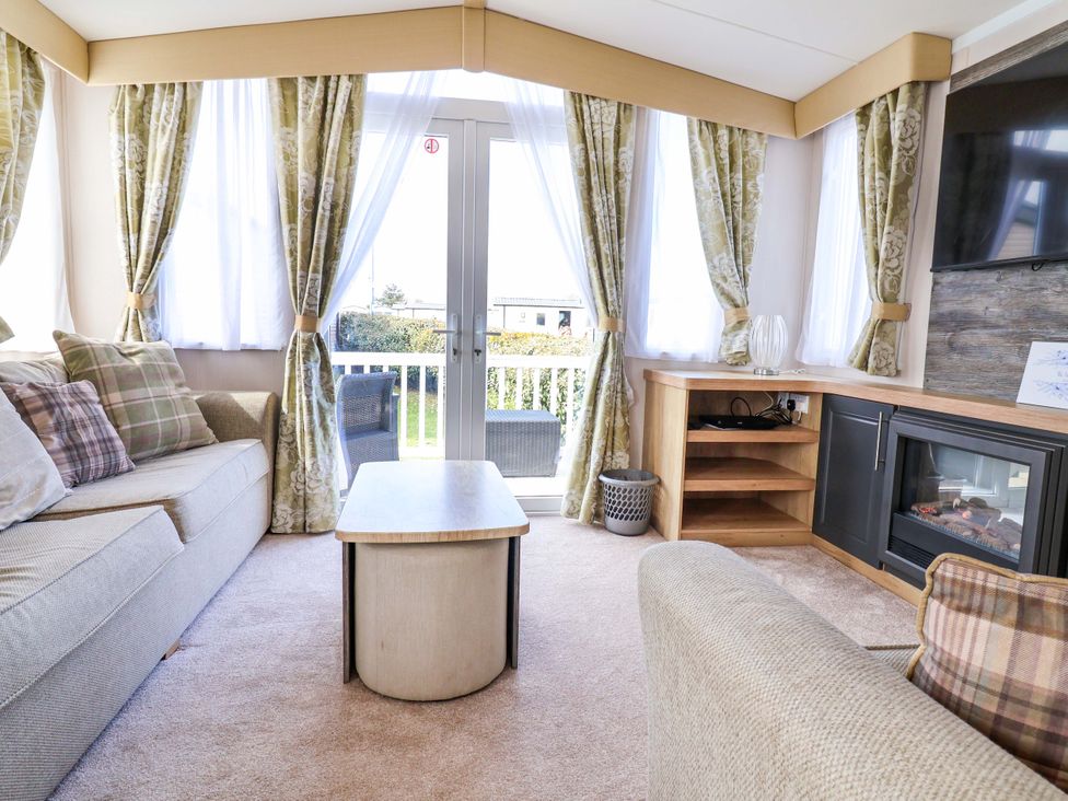 A living room with a sofa, coffee table and television at The Retreat in Prestatyn