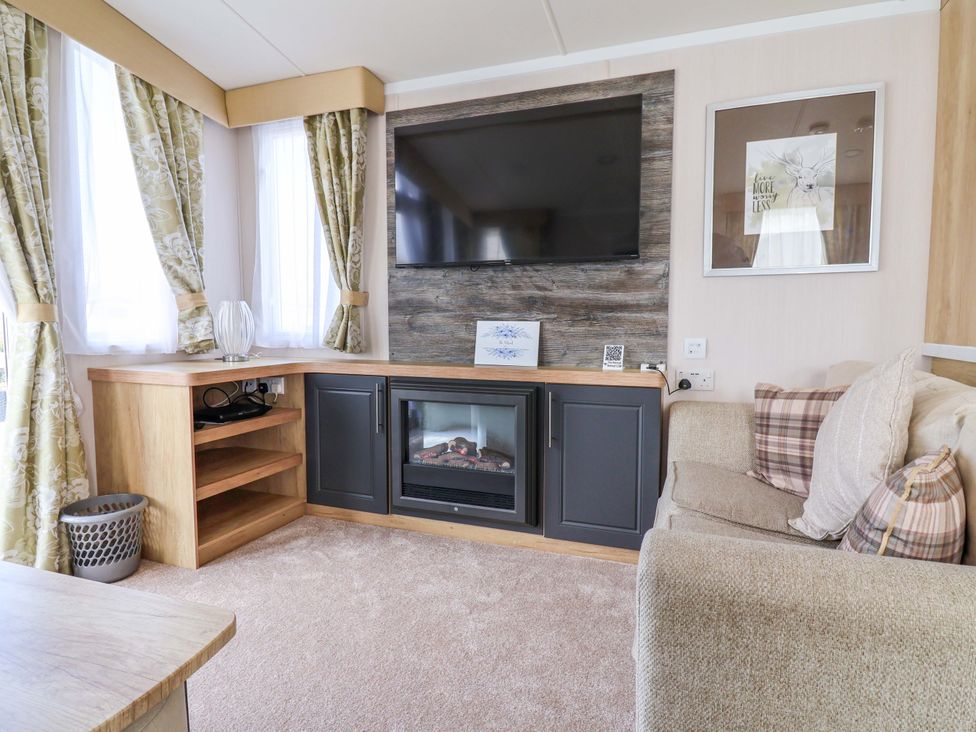A living room with a television and fireplace at The Retreat in Prestatyn