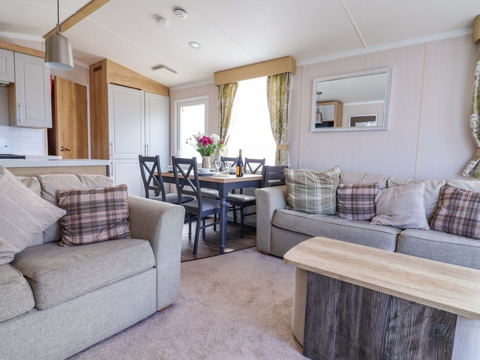 A living room with a sofa, table, and chairs at The Retreat in Prestatyn