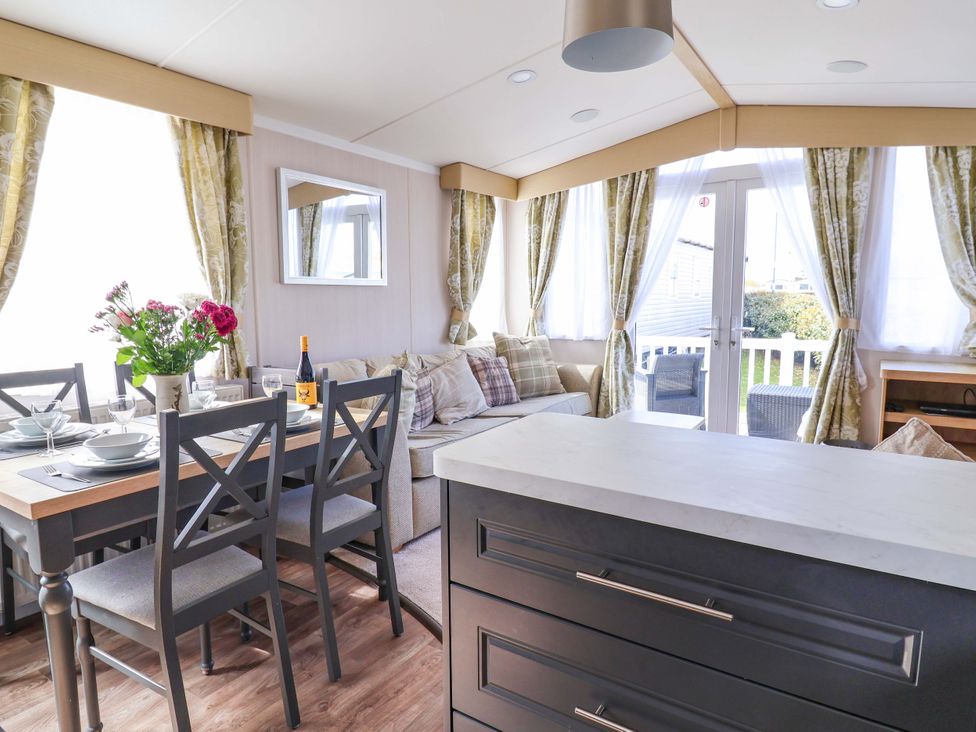 A living room with dining area and kitchen island at The Retreat in Prestatyn