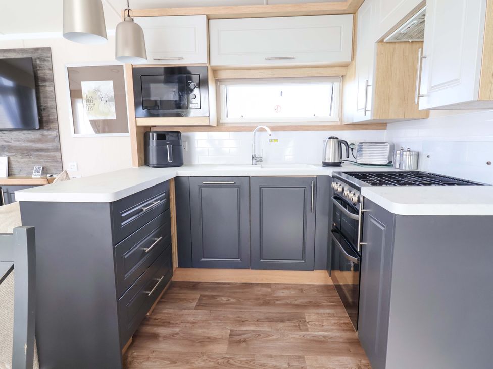 A kitchen with a stove, sink, and cabinets at The Retreat in Prestatyn