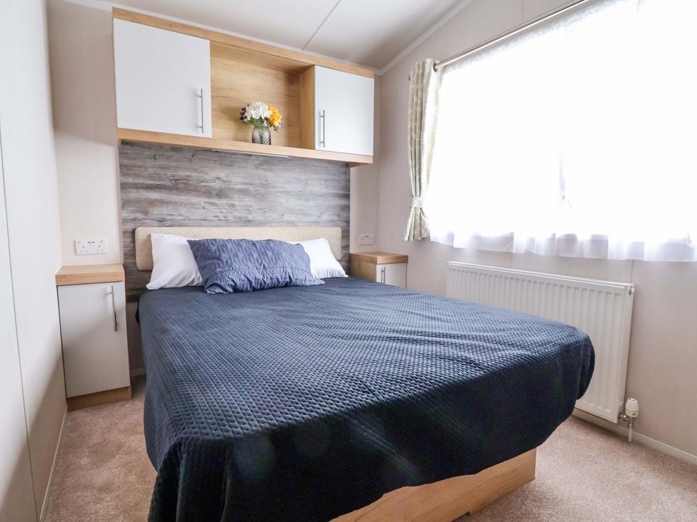 A bedroom with a bed and storage cabinets at The Retreat in Prestatyn