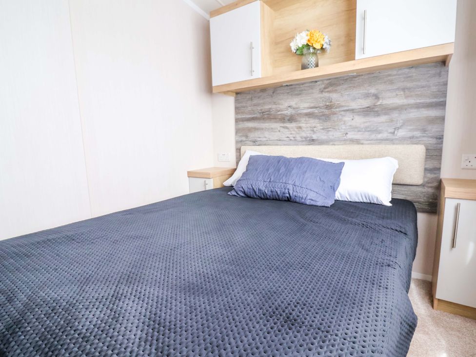 A bedroom with a bed and shelf above at The Retreat in Prestatyn