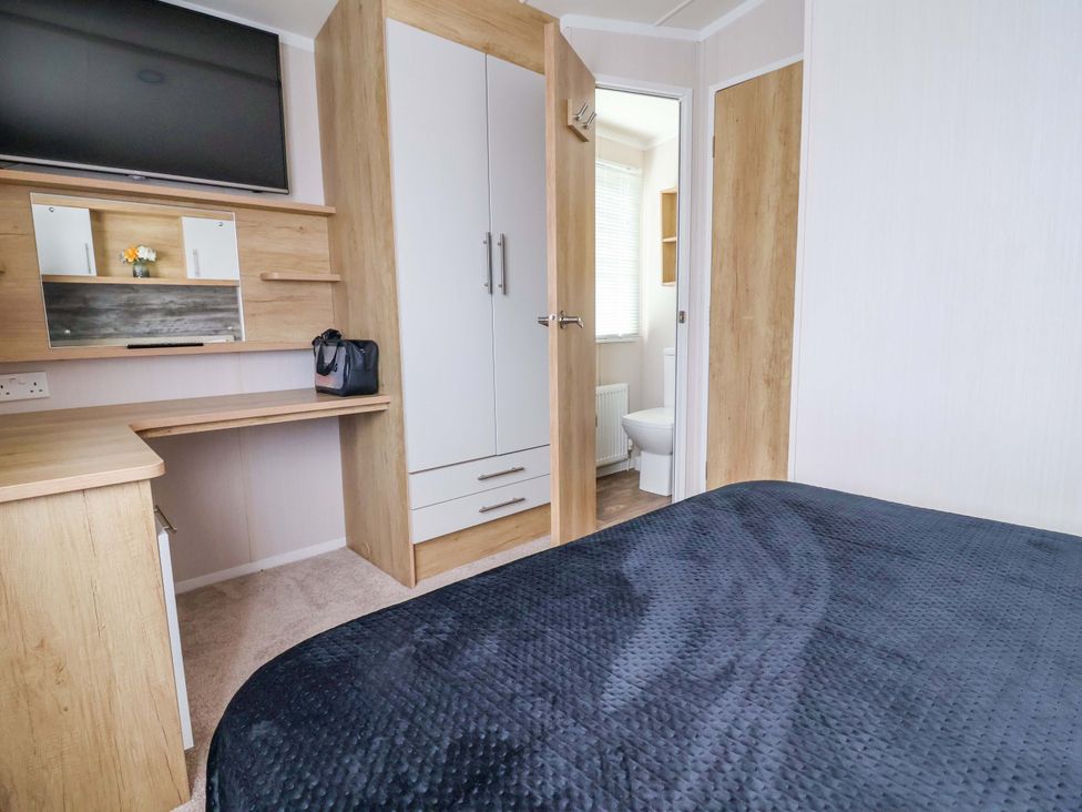 A bedroom with a desk and cupboard at The Retreat in Prestatyn