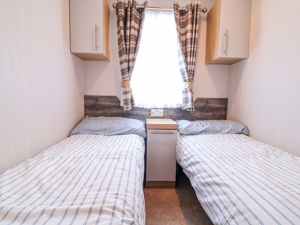 A bedroom with two beds and a bedside table at The Retreat in Prestatyn