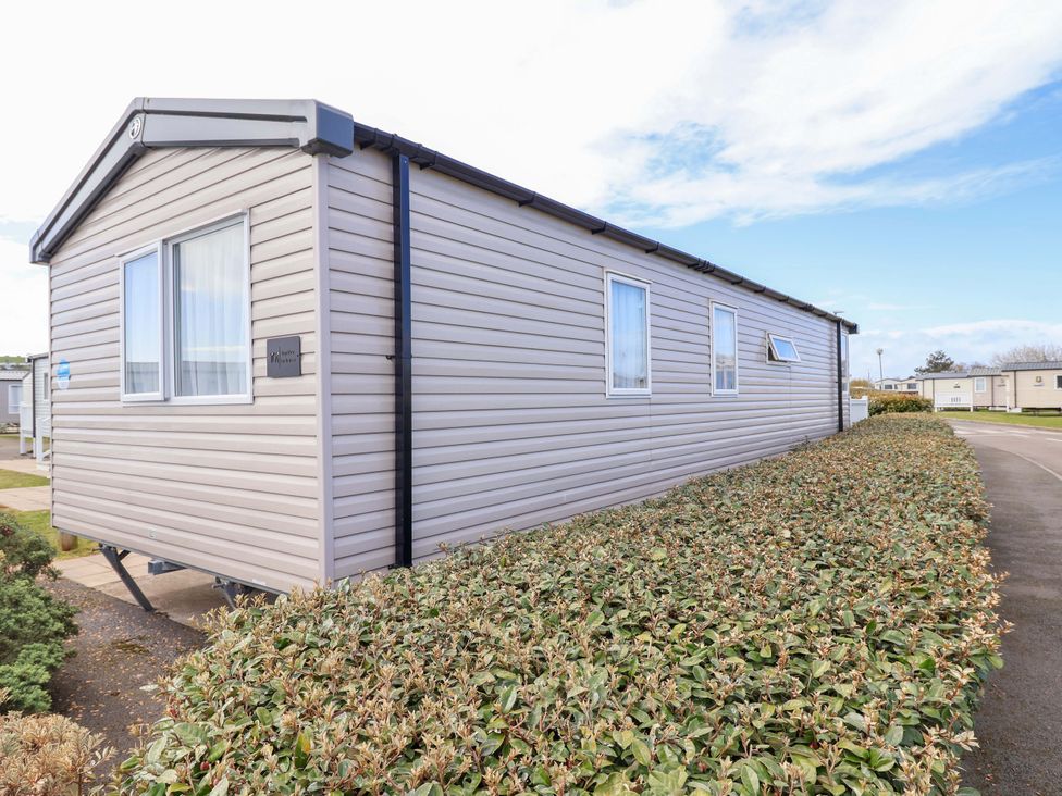 A mobile home with windows and bushes surrounding at The Retreat in Prestatyn