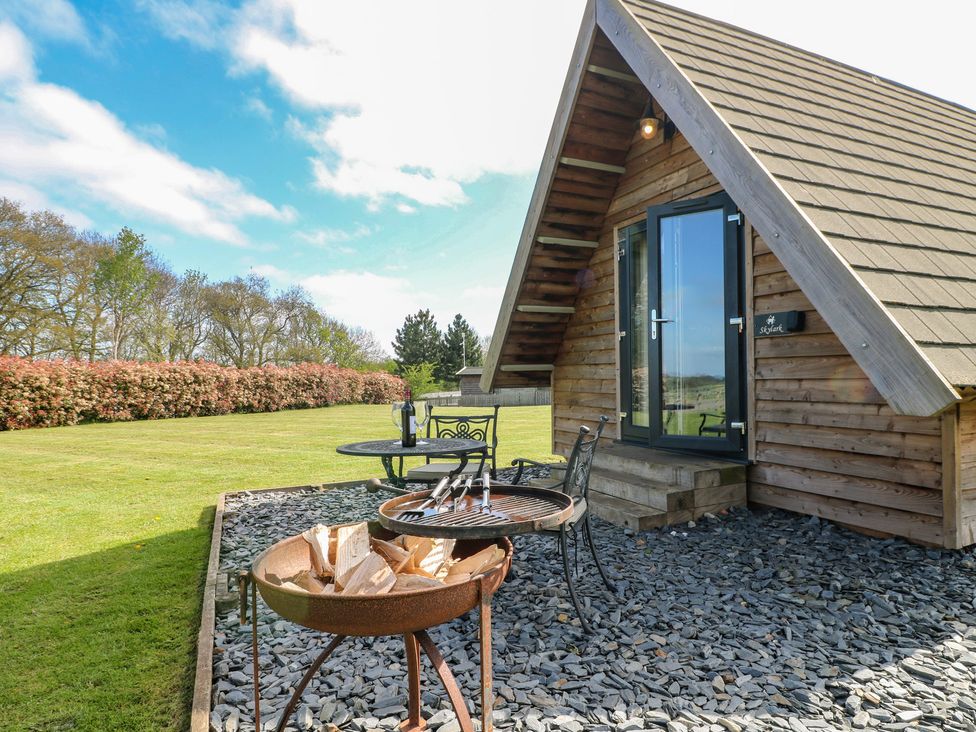A cabin with a grill and seating area at Skylark in Loughborough