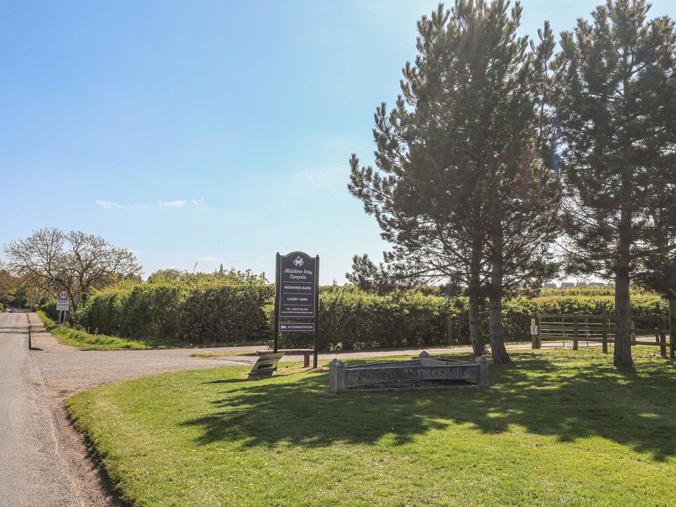 A sign for a campsite near a road surrounded by trees at Audisley Way Campsite in Loughborough