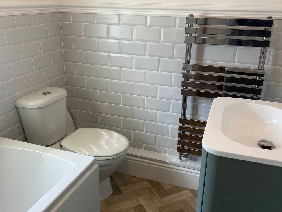 A bathroom with a toilet, bathtub, towel radiator, and sink at 3 Newboro Terrace Conwy