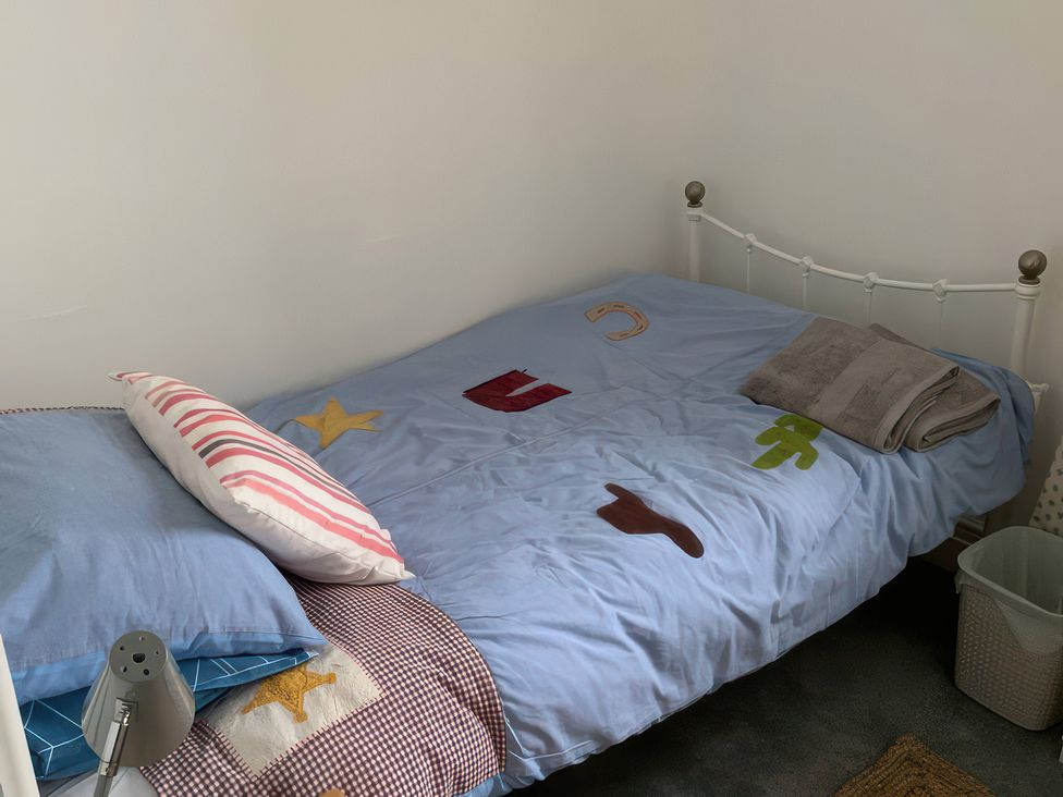 A bedroom with a bed, pillow, towel, and lamp at 3 Newboro Terrace in Conwy